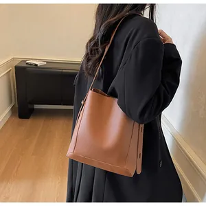 Detail of caramel lychee grain leather bucket bag paired with a black blazer
