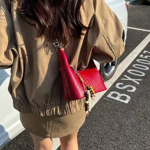 Red woven hobo bag with colorful bead tassel on a stylish khaki outfit background