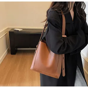 Close-up of brown litchi pattern leather texture and wide strap of the bucket bag