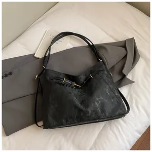 Close-up of black marble-textured tote bag with gold buckle and slim shoulder strap