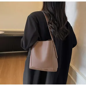 Detail of a brown leather bucket bag with litchi texture and fixed shoulder strap