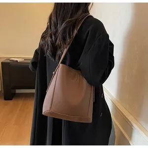 Detailed view of brown litchi pattern leather bucket bag with elegant stitching details