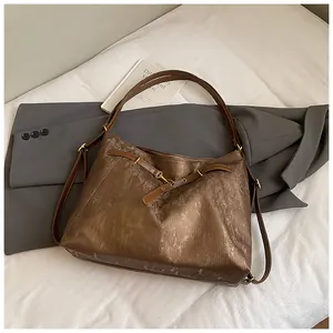 Detail of metallic brown tote bag showing vertical embossed texture and leather straps