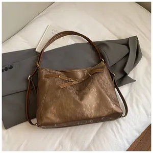 Detailed close-up of brown tote bag with metallic vintage texture and gold buckle
