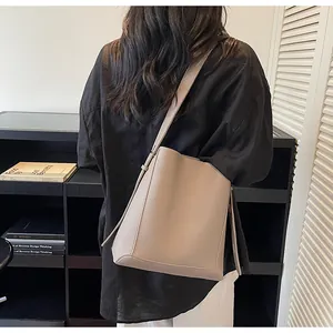 Detailed back view of a taupe lychee texture leather bucket bag worn by a model