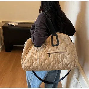 Detail der beigen gesteppten Reisetasche mit quadratischen Griffen und schwarzem Schultergurt