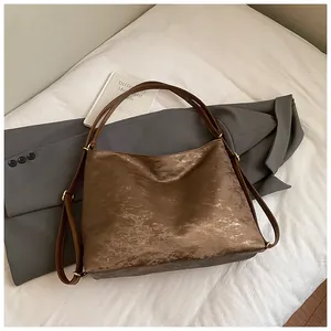 Close-up of brown vintage tote bag showing weathered metallic texture and leather straps