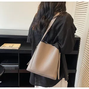 Detailed view of taupe litchi grain leather bucket bag showing texture and side drawstring