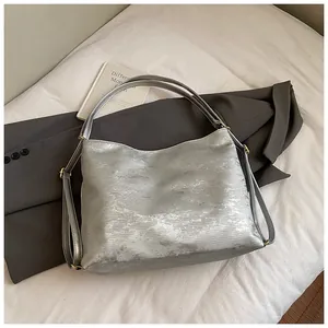 Close-up of silver tote bag with metallic brushed texture and golden metal hardware