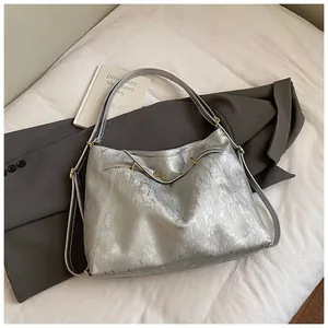Detail of silver metallic tote bag with vertical texture and gold chain strap