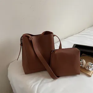 Brown lychee grain bucket bag set with matching pouch on white bedding lifestyle view