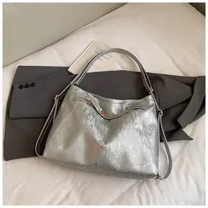 Detail of silver metallic hobo bag featuring fine texture and golden adjustable buckle