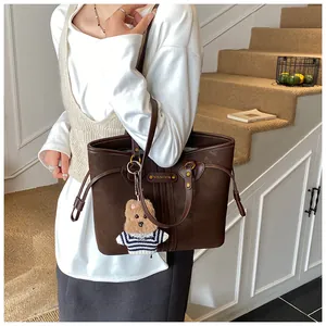 Détail du cabas en daim marron foncé avec boucle dorée et breloque ours en peluche
