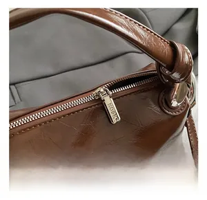 Detail of silver metal zipper with engraved logo on vintage brown glossy leather bag