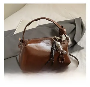 Detailed close-up of dark brown Boston bag with knotted handle and unique charms