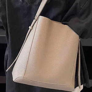 Minimalist beige pebble leather bucket bag for women with elegant shoulder strap