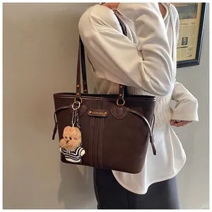 Détail d'un cabas vintage marron foncé avec ferrures dorées et breloque ours