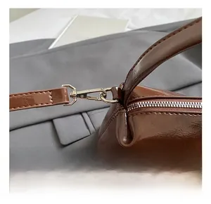 Close-up of polished silver metal hook and connector on vintage brown leather handbag
