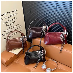 Detail view of glossy Boston handbags in four colors displayed on a leather sofa