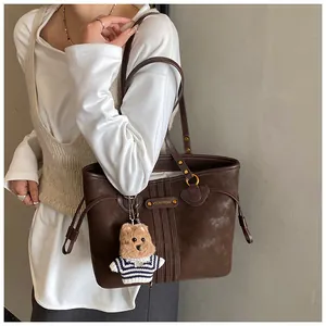 Détail d'un grand sac cabas marron foncé avec rayures et un petit charme en peluche