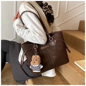 Détail du grand sac cabas marron foncé avec ferrures dorées et breloque ours en peluche