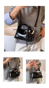 Close-up of black glossy Boston bag featuring silver hardware and a woven tassel detail