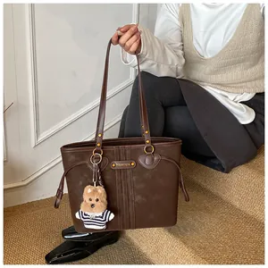Détail d'un sac cabas vintage marron foncé avec un ourson et des finitions dorées
