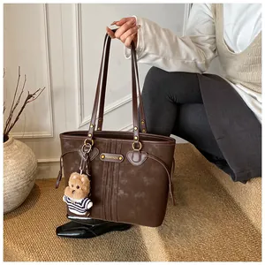 Détail d'un cabas vintage marron avec surpiqûres et pendentif en peluche pour chien