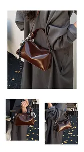 Detail of dark brown glossy leather crossbody bag with knot strap and woven rope charm