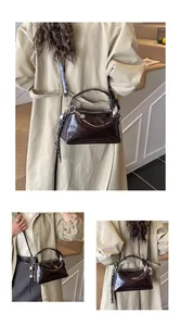 Detail view of glossy dark brown Boston handbag with silver zippers and woven ornament