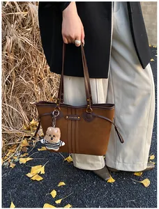 Sac fourre-tout marron texturé avec pendentif chiot dans un décor extérieur d'automne