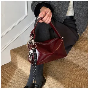 Detail of vintage burgundy glossy leather bag with silver hardware and chic charms