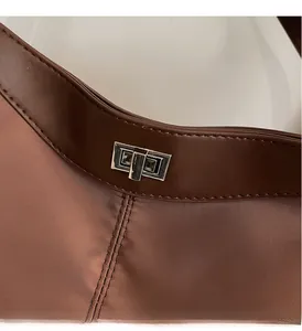 Detail of silver twist lock and premium stitching on brown leather crossbody bag