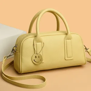 Classic yellow litchi leather Boston bag with smiley charm and crossbody strap for women