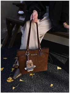 Détail du cabas en cuir mat marron foncé avec un charmant pendentif chien en peluche