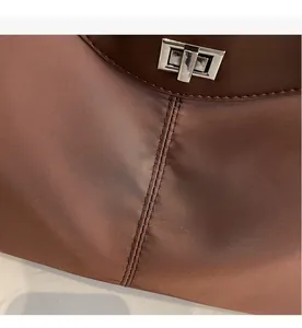 Detail view of brown nylon tote with leather edge, silver turn-lock and double stitching