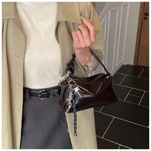 Close-up of shiny dark brown patent leather pillow bag with stylish decorative charms