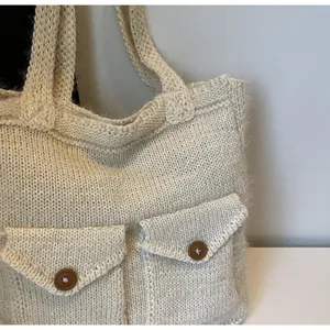 Détail d'un cabas en maille crème avec poches cargo et boutons marron vintage