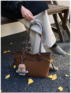 Grand sac cabas en cuir marron avec breloque ours sur fond de feuilles d'automne