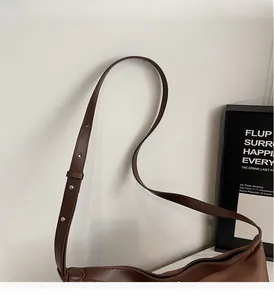 Close-up of adjustable strap with silver buckle on a brown textured leather tote bag