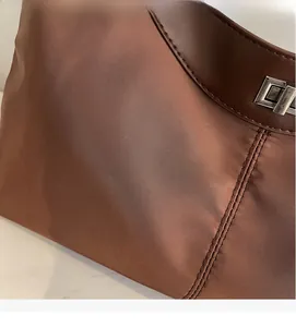 Detail of waterproof nylon fabric with silver metal lock on dark brown tote bag