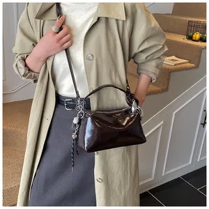 Detail of dark brown leather crossbody bag with silver metal ring and strap on a model