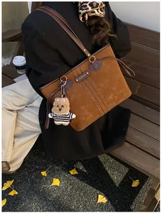 Détail d'un cabas en daim marron avec anses en cuir et charmant petit ours en peluche