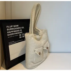 Détail du sac cabas en maille blanc crème avec texture tissée et poches à boutons