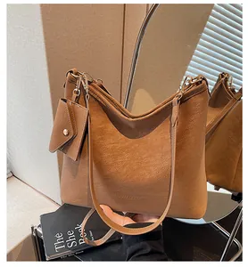 Detail of a brown leather shoulder bag featuring a mini card pouch and gold hardware
