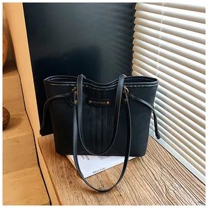 Détail du grand sac cabas noir avec coutures verticales et plaque logo dorée