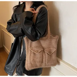 Détail d'un sac cabas en maille marron avec deux poches avant et texture en laine