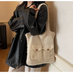 Détail du sac cabas en maille crème avec poches et boutons en bois porté par le modèle
