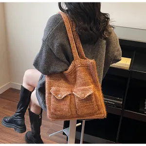 Gros plan sur le sac cabas en tricot marron avec deux poches avant et maille épaisse
