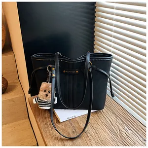 Détail d'un cabas noir en daim avec pendentif chiot et coutures sur surface en bois